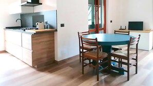 Une cuisine compacte dotée d’un îlot central, d’une table à manger avec des chaises et d’un téléviseur posé sur un meuble.