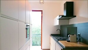 Une cuisine moderne avec des meubles blancs, un four encastré, une hotte noire et un plan de travail en bois.