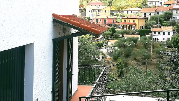 Un bâtiment blanc avec des volets verts et un toit recouvert de tuiles rouges.