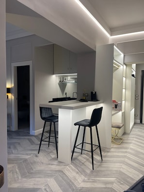 A modern kitchen with a central island, two bar stools, and a built-in wine rack.