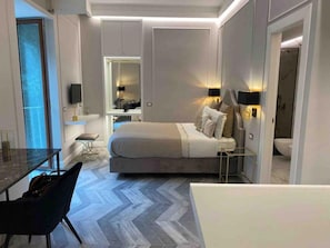 A modern hotel room with a bed, bedside tables, a desk, and a chair.