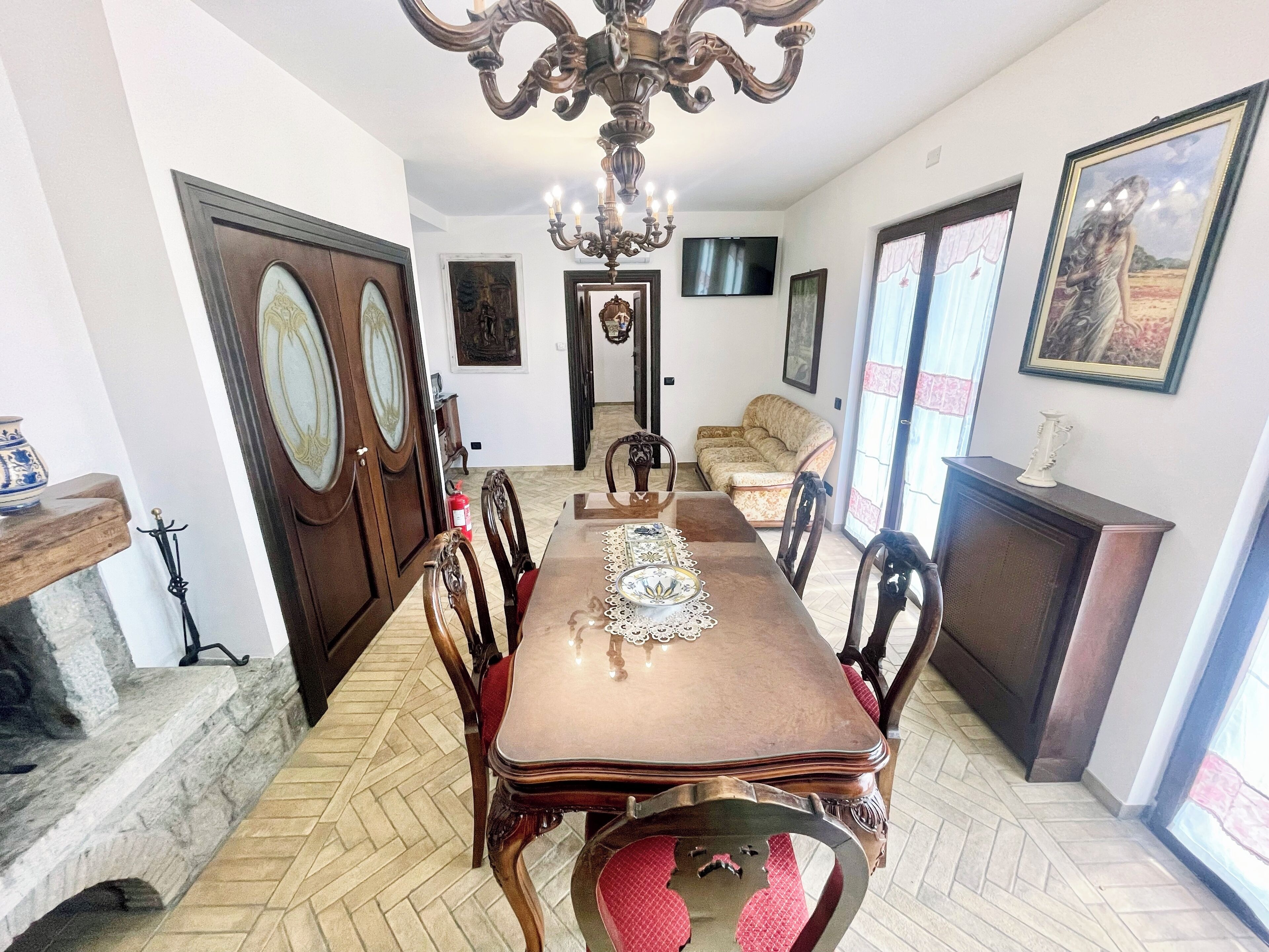 Un coin repas avec une table en bois, des chaises, un lustre et une cheminée.