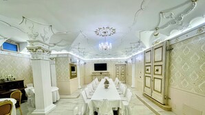 Een formele eetzaal met een lange tafel, stoelen en een kroonluchter.
