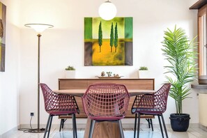 A dining area with a wooden table, two pink chairs, a floor lamp, a painting, and a potted plant. - Vacation Rental Seeblick Pocobelli in Melide (Melide)