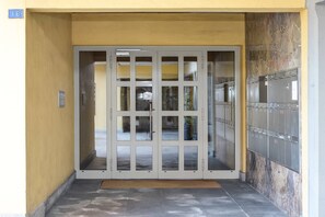 A building entrance with a glass door, a keypad, and a wall-mounted locker. - Vacation Rental Seeblick Pocobelli in Melide (Melide)