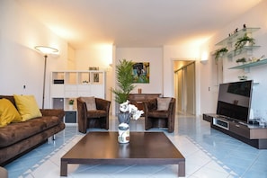 A modern living room with a sofa, armchairs, a coffee table, and a TV. - Vacation Rental Seeblick Pocobelli in Melide (Melide)