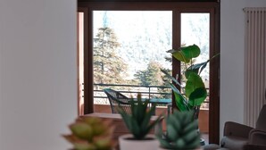 A balcony with a view of trees and a mountain, a table with chairs, and potted plants. - Vacation Rental Seeblick Pocobelli in Melide (Melide)