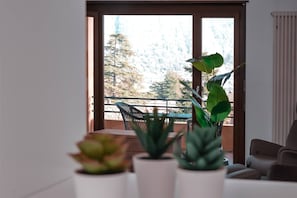 A room with a balcony, a dining table, and potted plants. - Vacation Rental Seeblick Pocobelli in Melide (Melide)