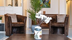A modern lobby with two brown leather sofas, a white vase with white flowers, and a large green plant. - Vacation Rental Seeblick Pocobelli in Melide (Melide)
