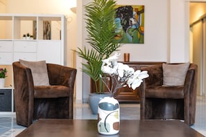 A modern living room with two brown sofas, a coffee table, a potted plant, and a painting on the wall. - Vacation Rental Seeblick Pocobelli in Melide (Melide)