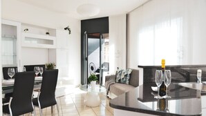 A modern kitchen with a black countertop, a dining area with black chairs, and a sofa with a geometric pillow.
