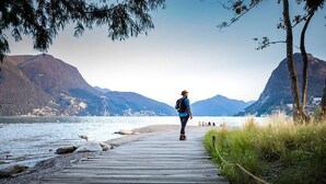 A wooden boardwalk leading to a body of water with mountains in the background.