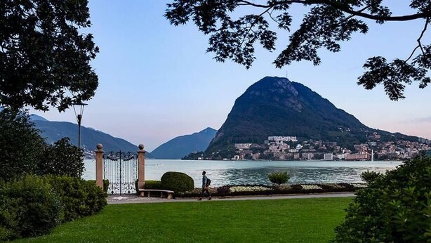 A park with a lake, a mountain, and a city in the background.