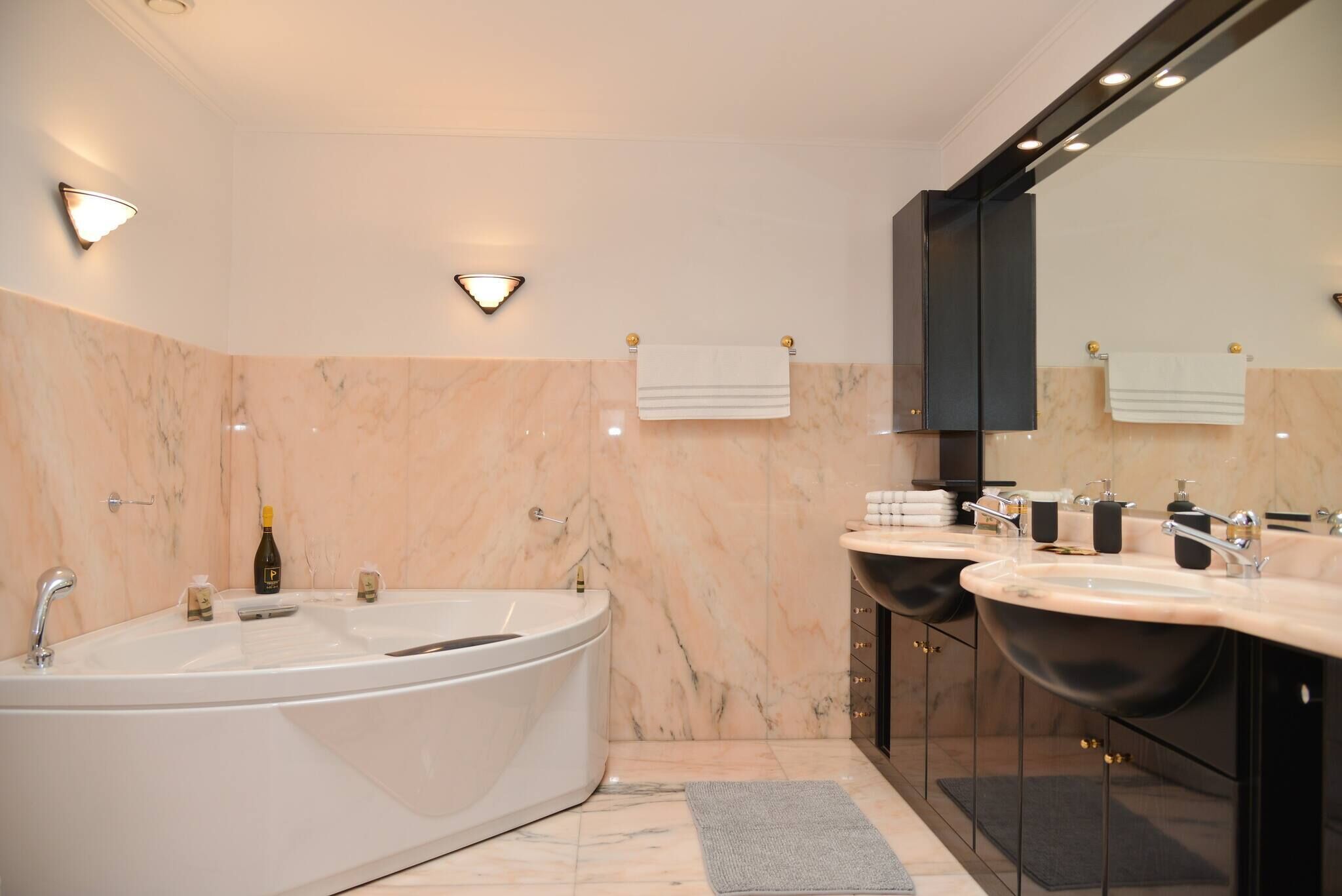 A modern bathroom with a freestanding bathtub, two sinks, and a large mirror.