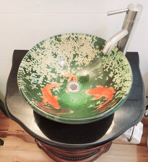 A green ceramic sink with a silver faucet on a black countertop.
