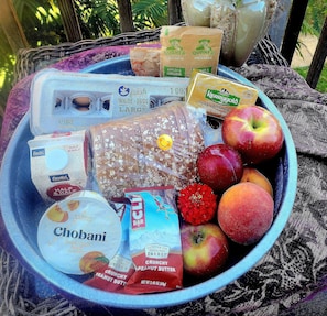 A variety of food items including eggs, bread, apples, and energy bars in a bowl.