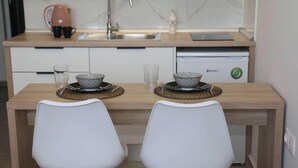 Una cocina moderna con encimera de madera, dos sillas blancas y un lavavajillas.