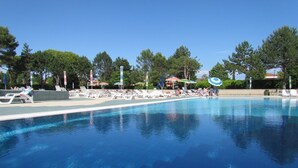 A swimming pool with lounge chairs and umbrellas, surrounded by trees. - Comfy Flat for Pool's Lovers - Beahost (San Michele al Tagliamento)