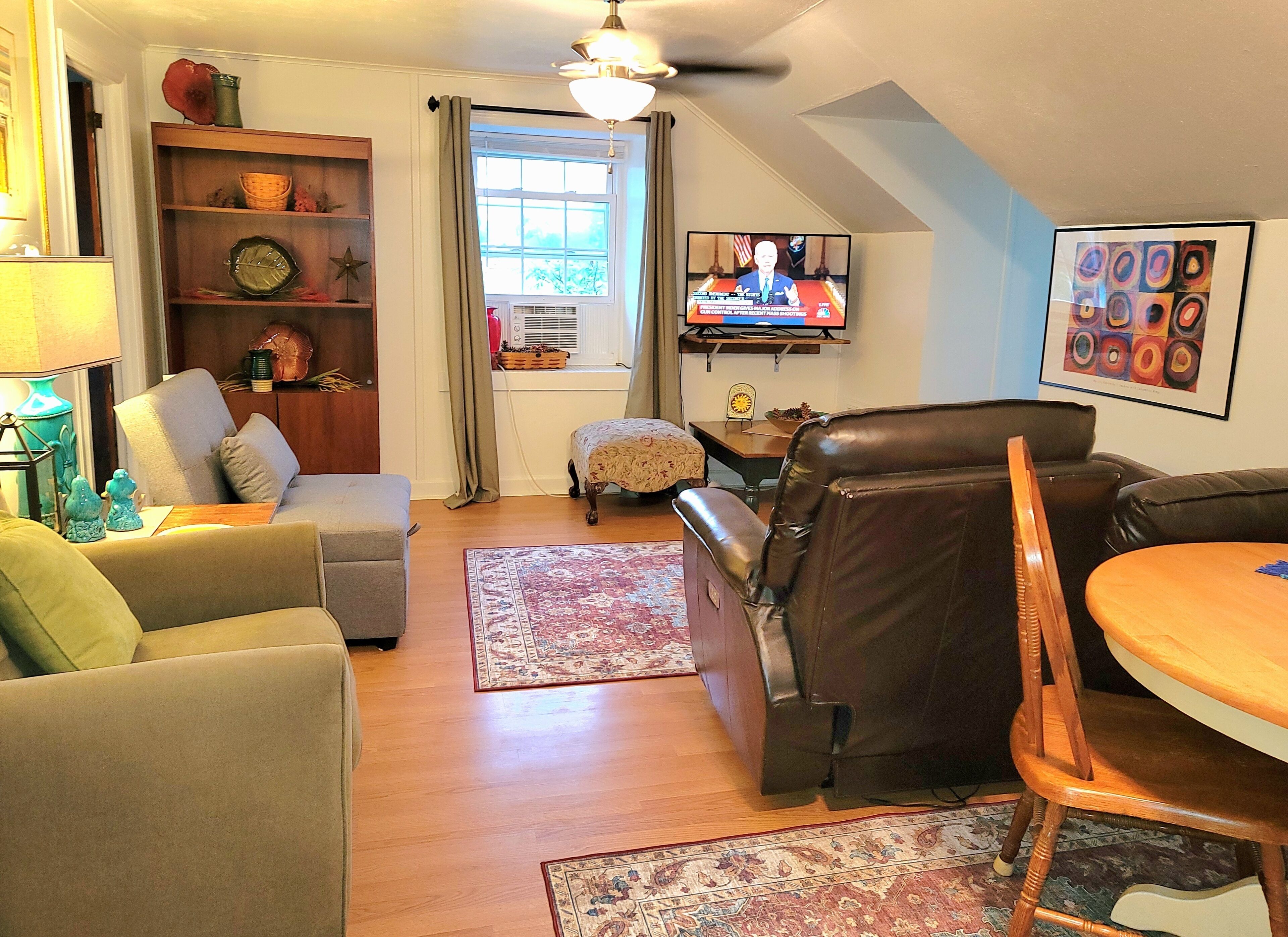 A living room with a sofa, armchairs, a coffee table, a TV, and a bookshelf.