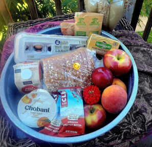 A variety of food items including eggs, bread, apples, and energy bars in a bowl.
