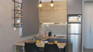 A modern kitchen with a stainless steel refrigerator, a microwave, a kettle, and two black chairs at a wooden table. - New Studio 3 Downtown Thessaloniki-fully Equipped (Thessaloniki)