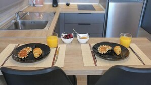 A breakfast setup with waffles and croissants, two bowls of fruit, and glasses of orange juice. - New Studio 3 Downtown Thessaloniki-fully Equipped (Thessaloniki)