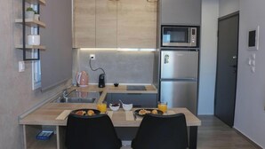 A compact kitchen with a microwave, refrigerator, and a small sink. There are two chairs at a table with breakfast items. - New Studio 3 Downtown Thessaloniki-fully Equipped (Thessaloniki)