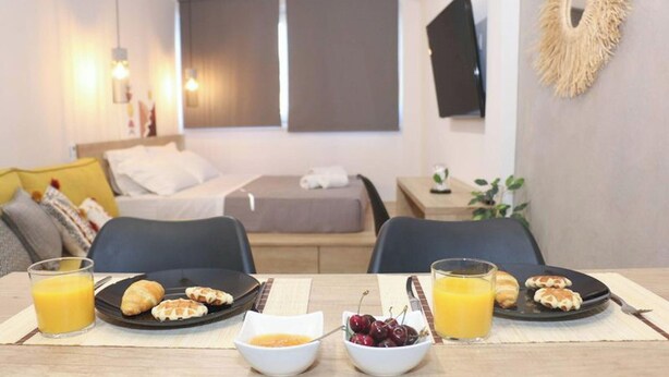 A hotel room with a bed, bedside tables, a TV, and breakfast setup with plates of pastries and glasses of orange juice. - New Studio 3 Downtown Thessaloniki-fully Equipped (Thessaloniki)