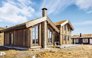 A wooden cabin with large windows, a stone chimney, and a thatched roof. - 4 bedroom beautiful home in øyer (Øyer)