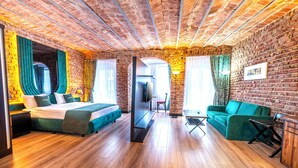 A room with a brick wall, wooden flooring, a bed, a sofa, a desk, and a mirror. - Karakoy Aparts Hotel (Istanbul)