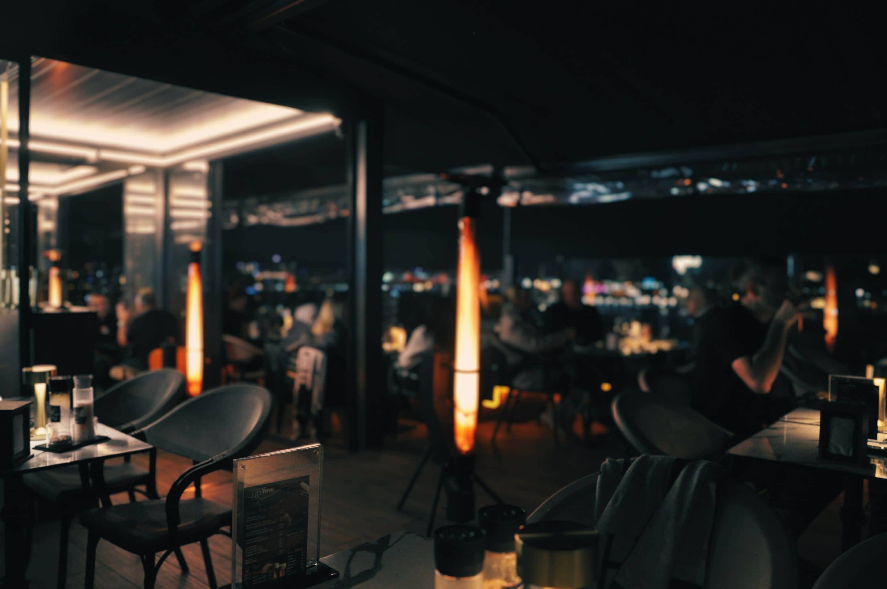 Un espace de restauration intérieur avec des tables et des chaises, un tableau affichant le menu et une vue sur le paysage urbain.