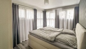 Une chambre à coucher de taille réduite, avec un lit, des rideaux et une fenêtre.