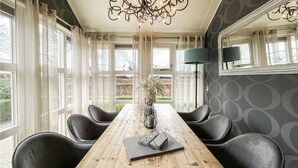 Un coin repas avec une table en bois, des chaises noires, un vase de fleurs et un lustre.