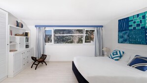 A bedroom with a large bed, a window with curtains, a bookshelf, and a chair. - Villa Mariuccia Apartment Bea J (Capri)