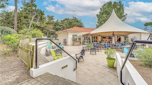 Een patio met buitenmeubels en een overdekt gedeelte.