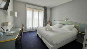 A hotel room with a bed, a desk, a chair, a TV, and a window with curtains. - Logis Hôtel Sully le Château (Saint-Père-sur-Loire)