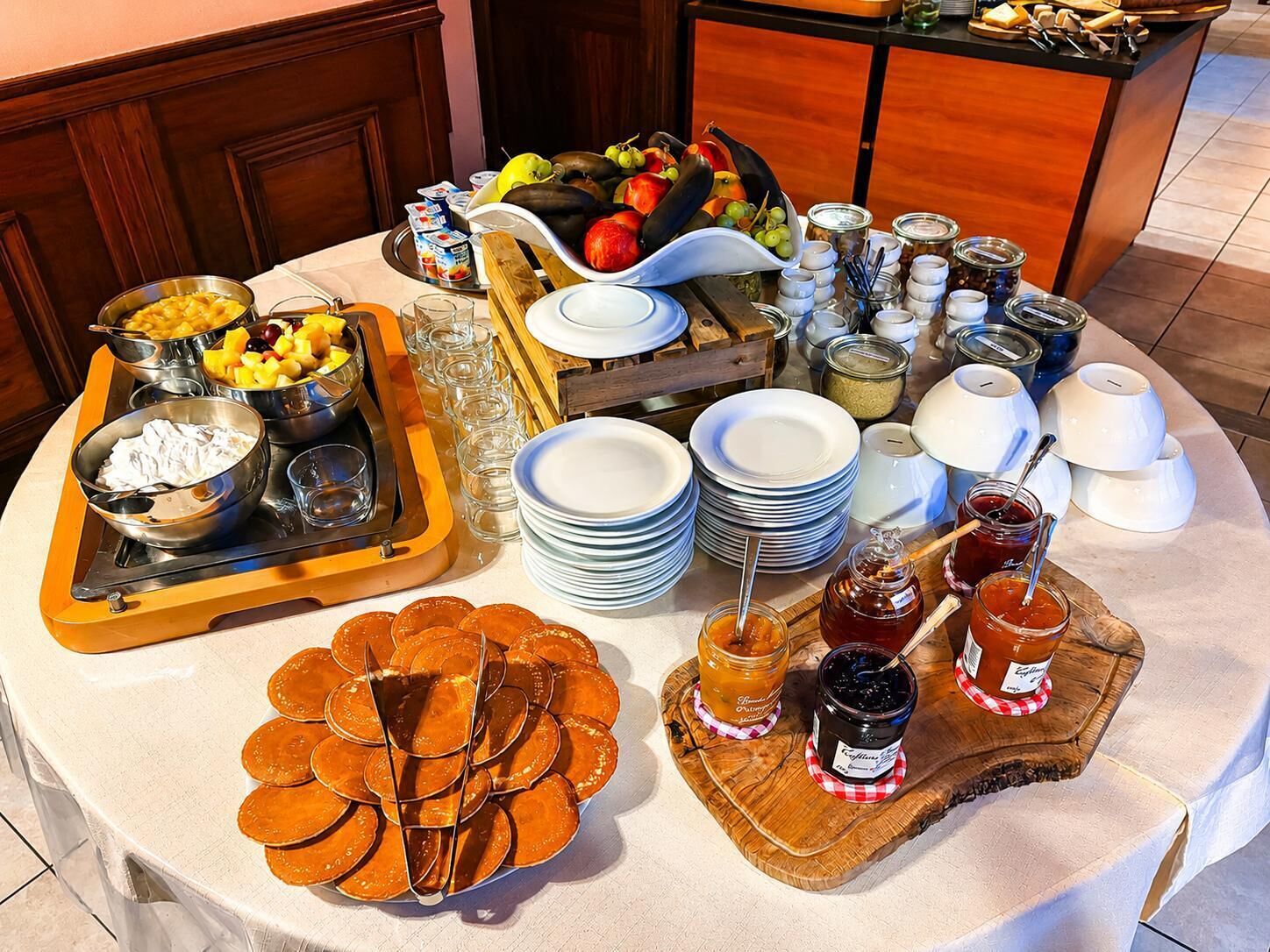 A breakfast buffet setup with various food items, plates, and condiments.