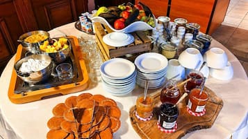 A breakfast buffet setup with various food items, plates, and condiments.