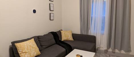 Ein modernes Wohnzimmer mit einem grauen Ecksofa, einem weißen Couchtisch und einem gemusterten Teppich.