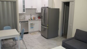 A compact kitchen with white cabinets, a stainless steel refrigerator, a sink, and a dining area with a table and chairs. - Fully Stocked Tampa Apartment (Tampa)