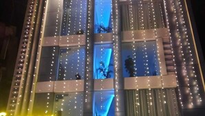 A multi-story hotel with a 'Sea port' sign, balconies with string lights, and a visible entrance with steps and potted plants. - Hotel Sea Port (Port Blair)