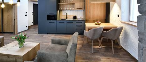 A modern kitchen with wooden cabinets, a dining area with a table and chairs, and a sofa.