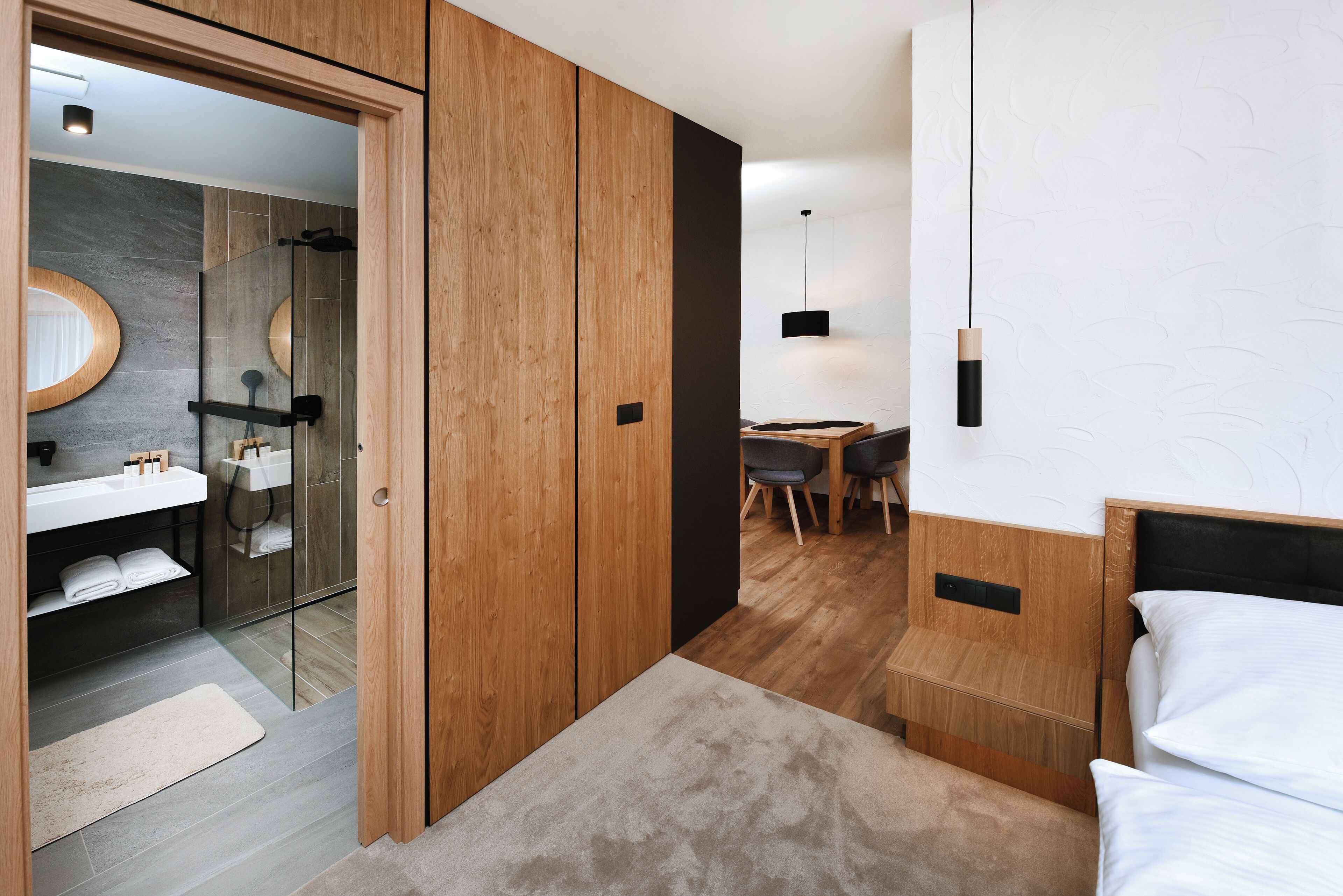 Un dormitorio moderno con un armario de madera, una mesita de noche, una silla y una cama.