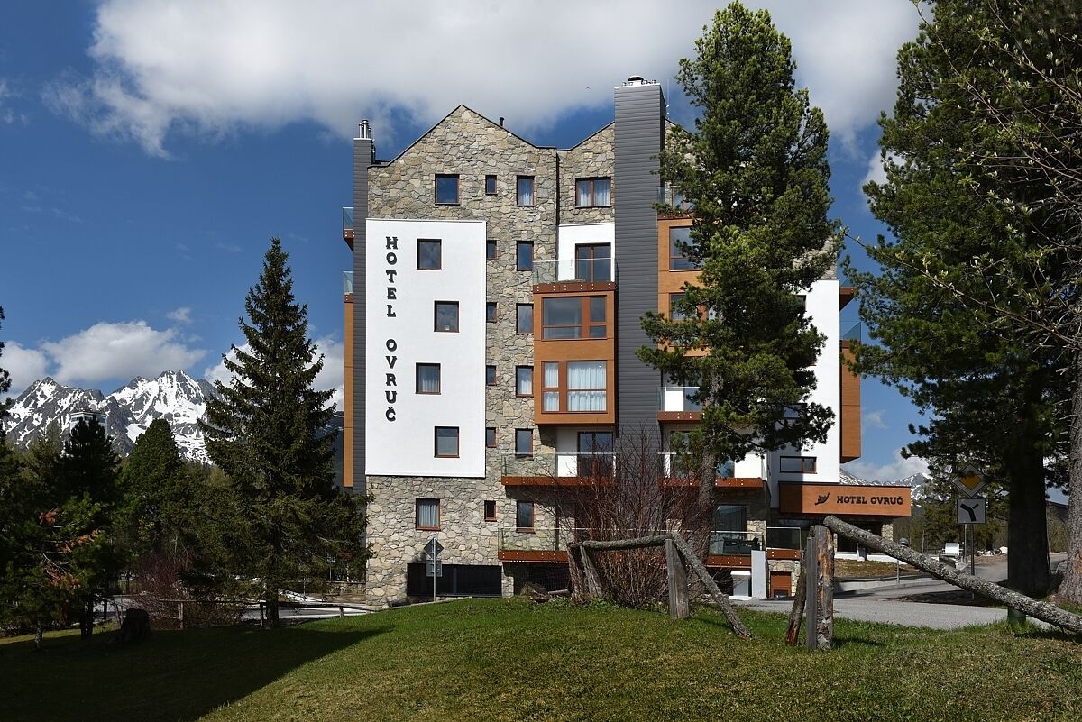 Ein mehrstöckiges Hotel mit einer Stein-Fassade, zahlreichen Fenstern und einem Schild mit dem Namen 'Hotel Ovrug'.