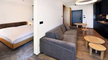 A modern room with a bed, a sofa, a dining table, and a kitchen area.