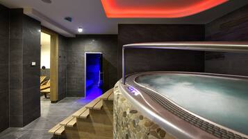 Un espace spa moderne avec un mur en pierre, un jacuzzi et des marches en bois menant à un espace de détente.