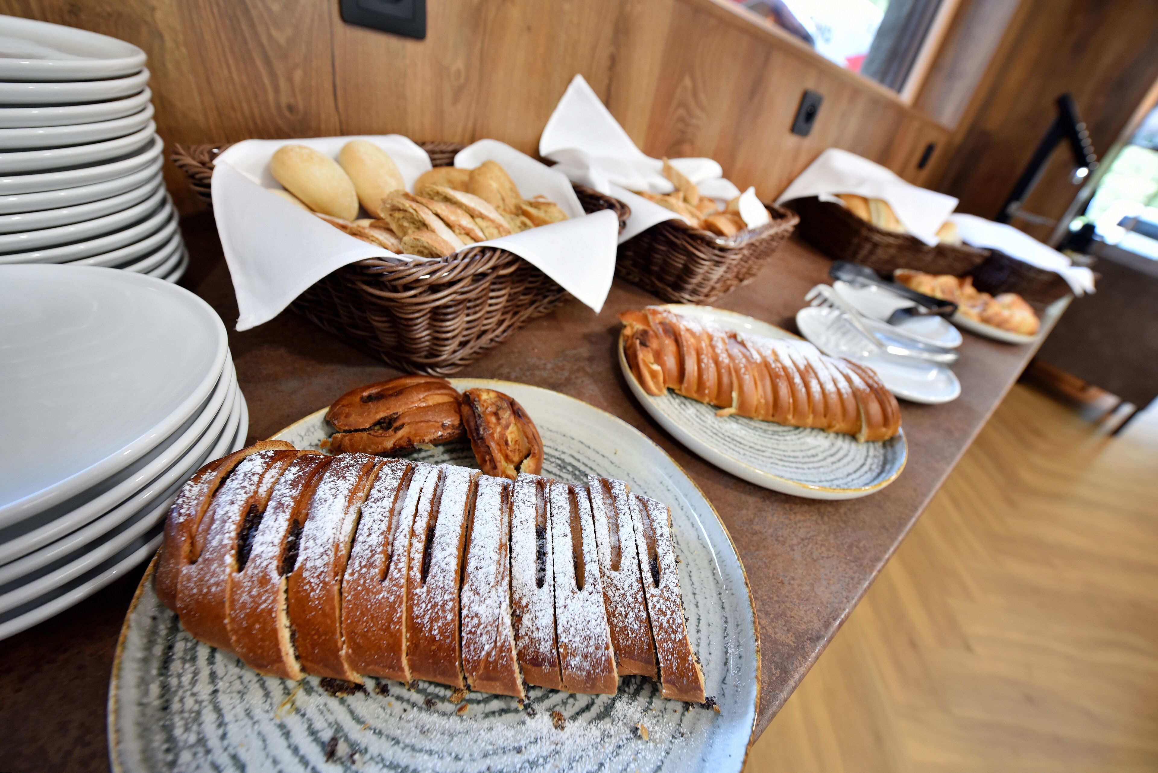 Una mesa de buffet con diversos panes y pasteles, incluyendo un pan con una capa de azúcar glas.