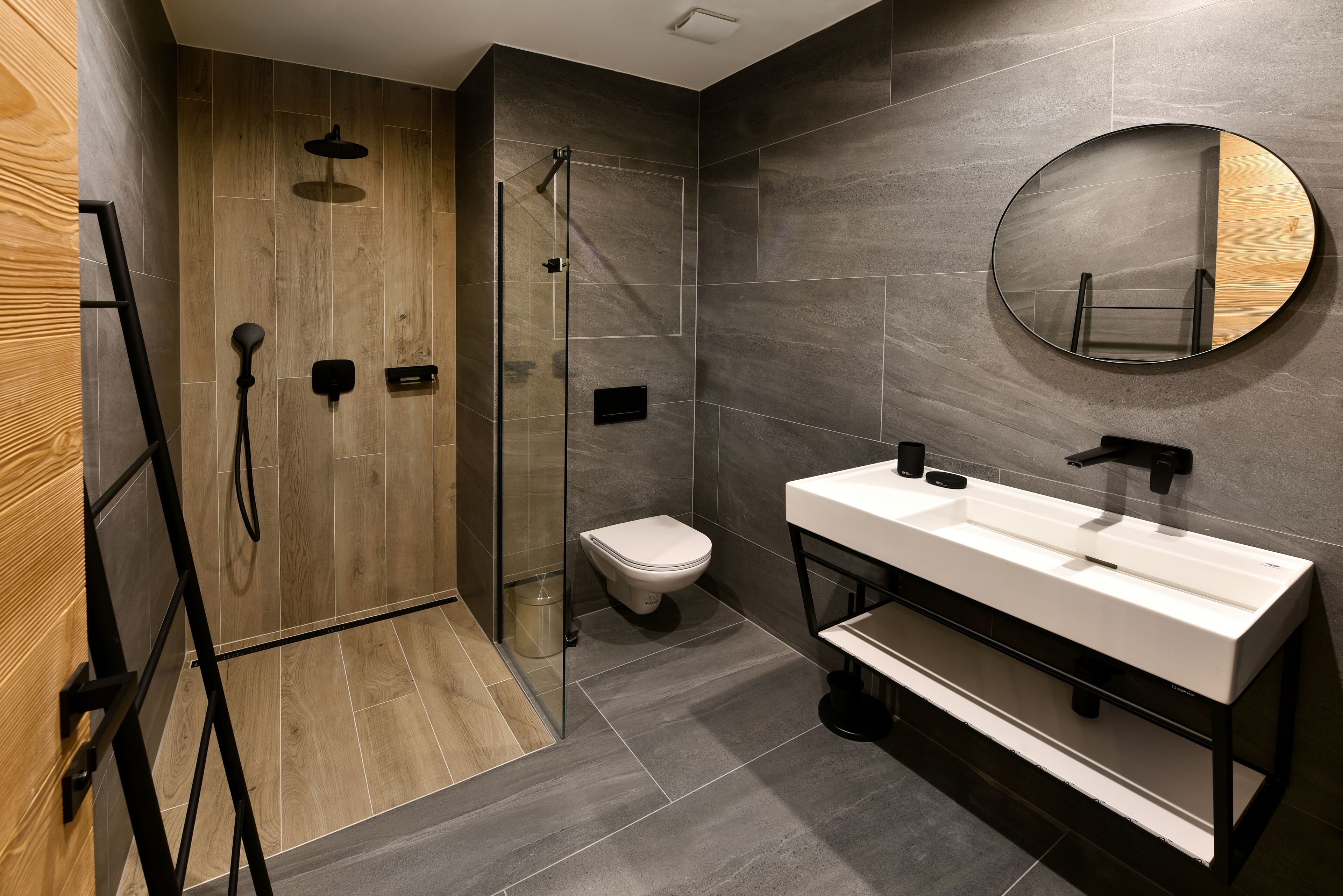 A modern bathroom with a wooden shower enclosure, a toilet, and a large mirror.