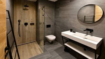 A modern bathroom with a wooden shower enclosure, a toilet, and a large mirror.