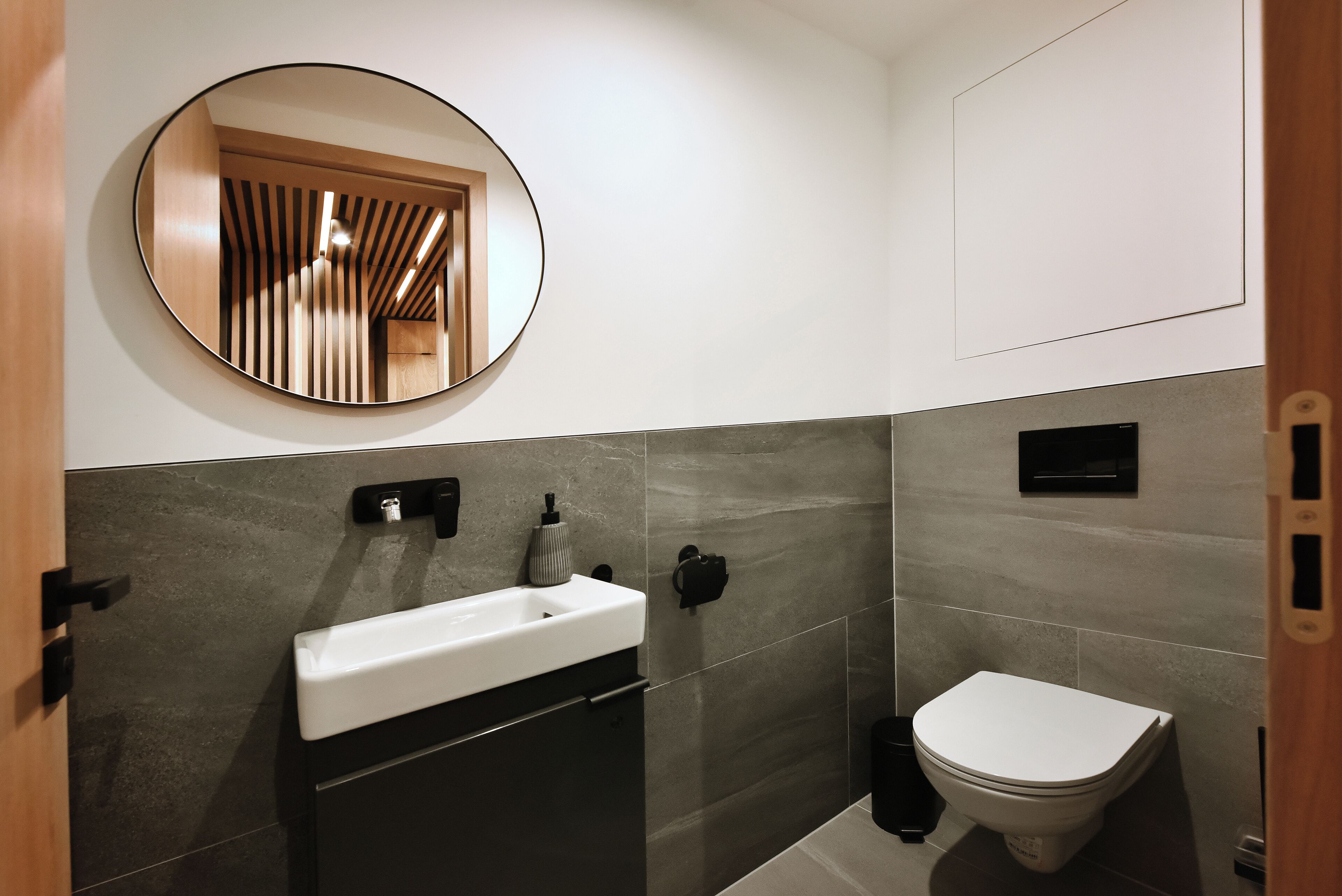 Un baño moderno con un espejo redondo, un lavabo blanco y un inodoro.